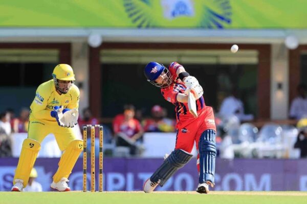 A batter plays an aggressive shot while the Chennai Super Kings wicketkeeper stays alert behind the stumps during a cricket match.